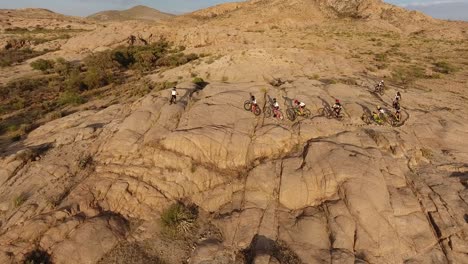 drone shot following cyclist people on a bicycle race in the desert mountains