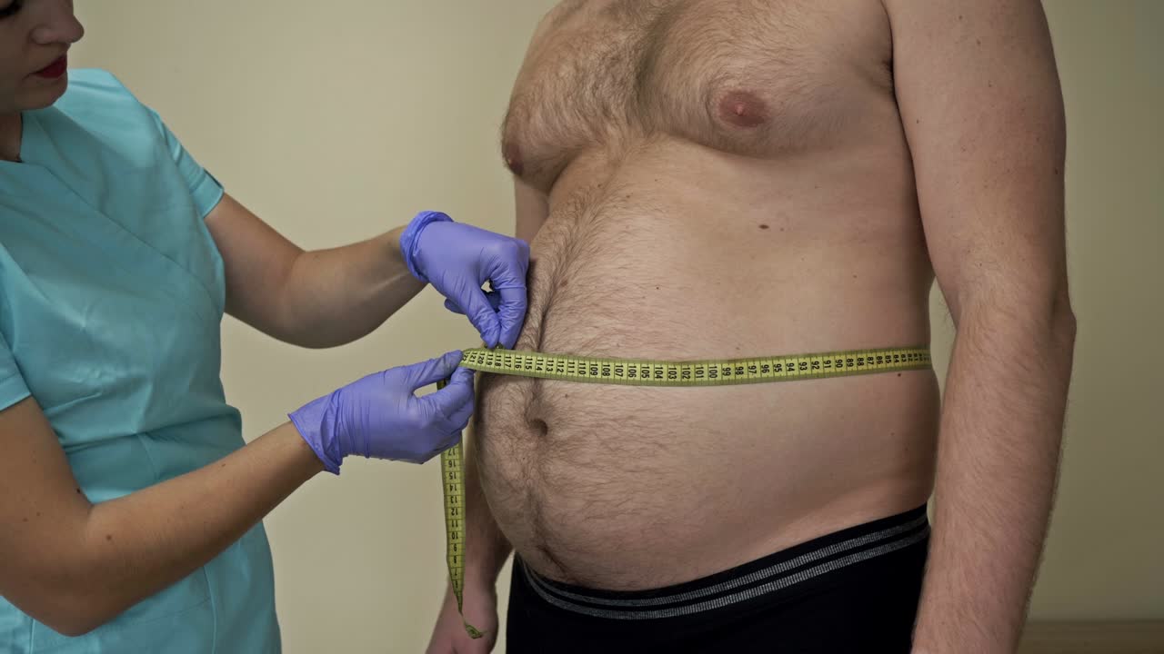 el médico mide la circunferencia abdominal de un paciente masculino gordo. problemas de sobrepeso