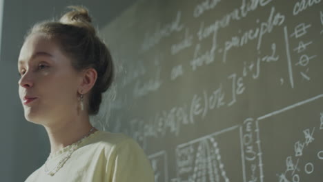 young woman standing by a chalkboard with formulas
