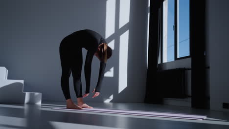mujer haciendo estiramientos de yoga en un estudio brillante