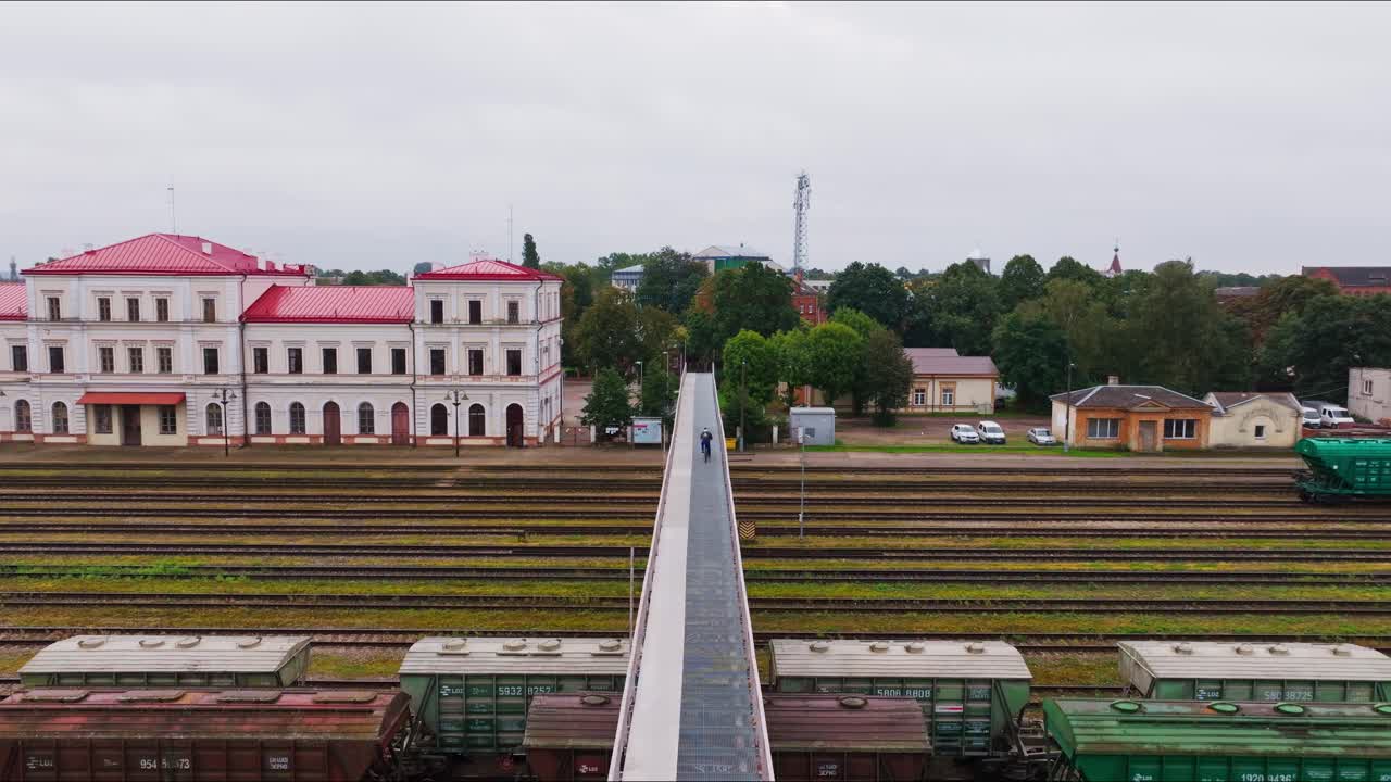 Plano de estabelecimento, ciclista atravessando a ponte ferroviária de Liepaja revelando as linhas da estação