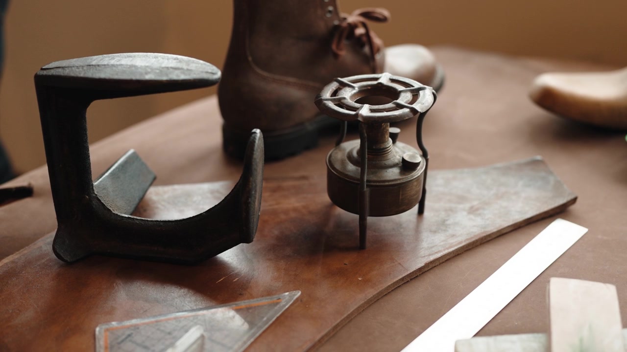 Cast Iron Cobbler Stand and Brass Spirit Burner beside Leather Boot on a Wooden Workbench