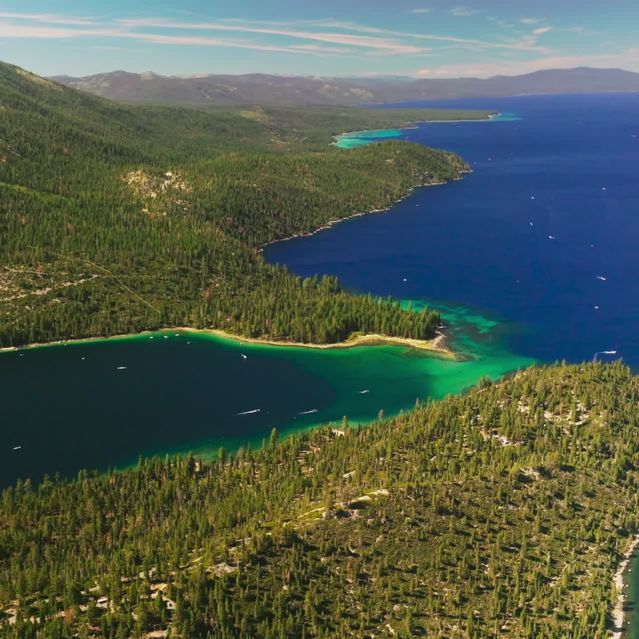 Different shades of blue in the waters of Lake Tahoe, California, USA. Amazing scenery of the lake and rocky wooded shore from aerial view