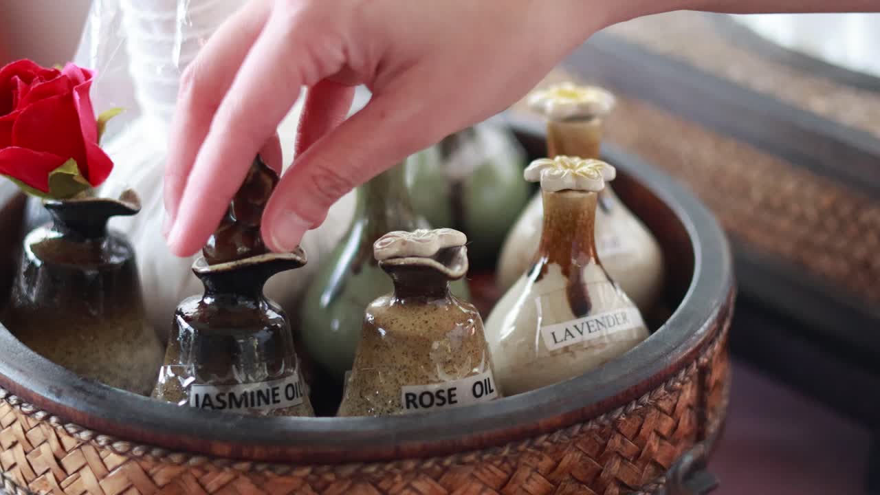 A hand selects and tests essential oils in a serene spa setting in Phuket, Thailand, under soft natural lighting