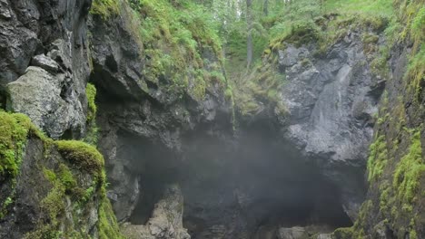 misty cave entrance in a mountainous forest