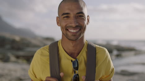 portrait of happy bald hispanic man smiling at beach wearing yellow shirt