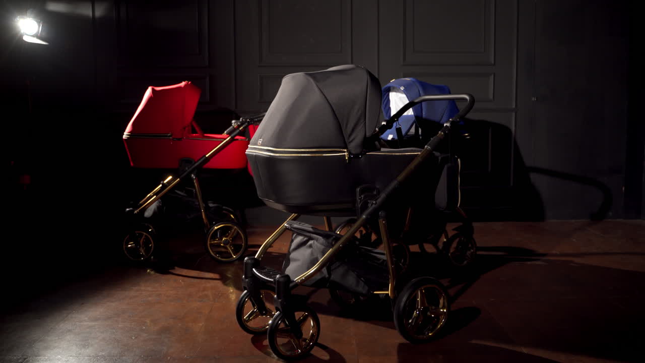 Beautiful new prams displayed in a room. Baby strollers moving at the dark space background.