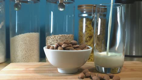 Almond-Milk-Being-Poured-into-a-Glass-with-a-Bowl-of-Almonds