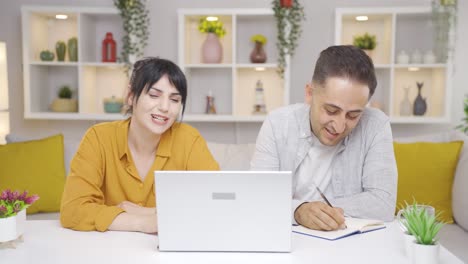 una pareja feliz trabajando en una computadora portátil.