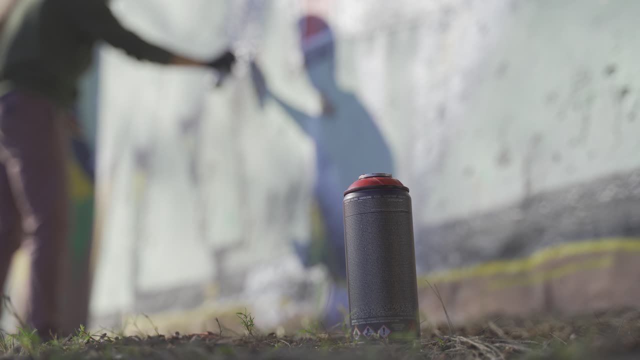 초점이 맞지 않는 남자가 벽에 낙서를 하고 있다