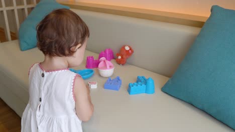 adorable asian toddler playing with her toys on a couch