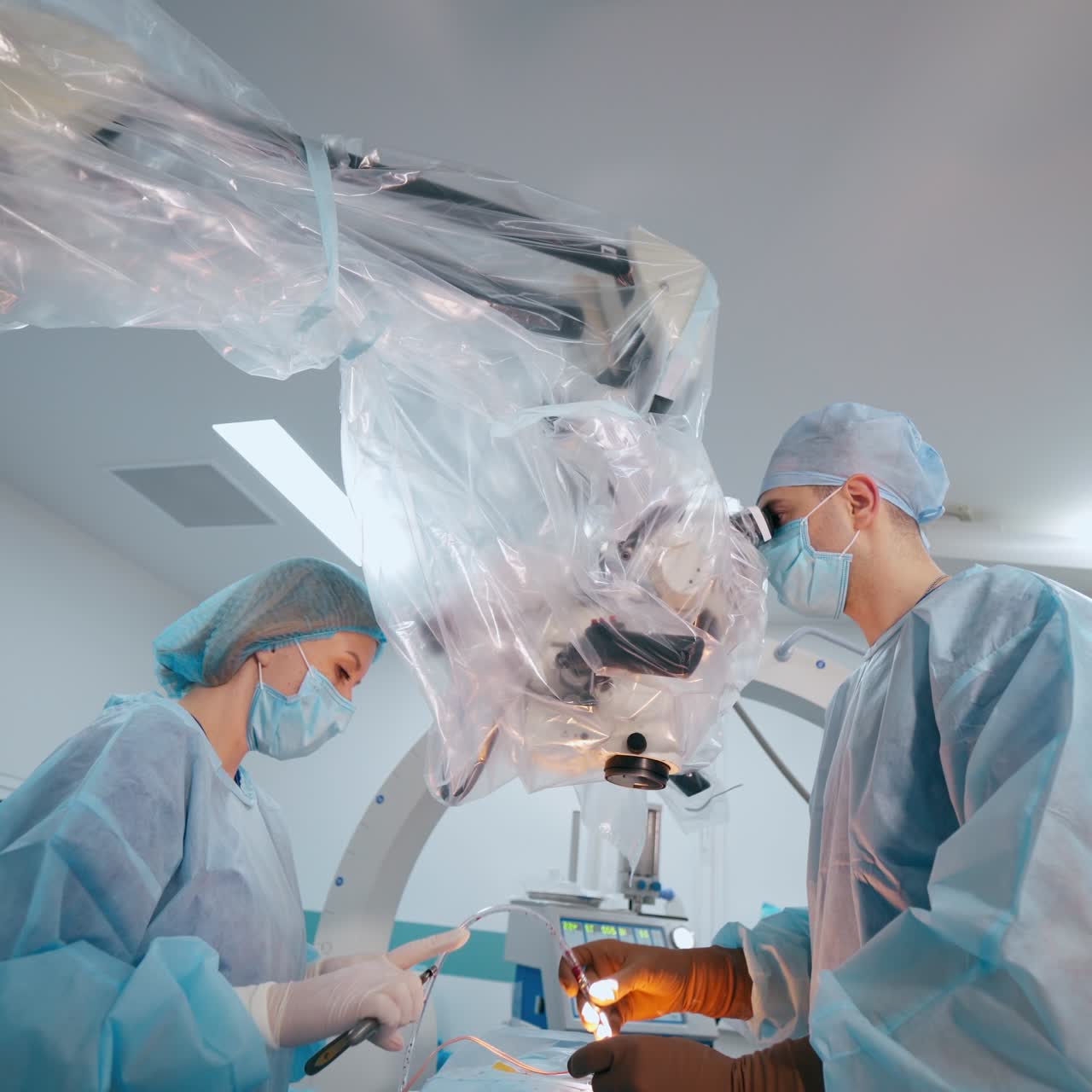 Doctors conduct a microsurgical operation. Professional specialist treats the patient. Female assistant gives medical instruments to a doctor in the operating theater.