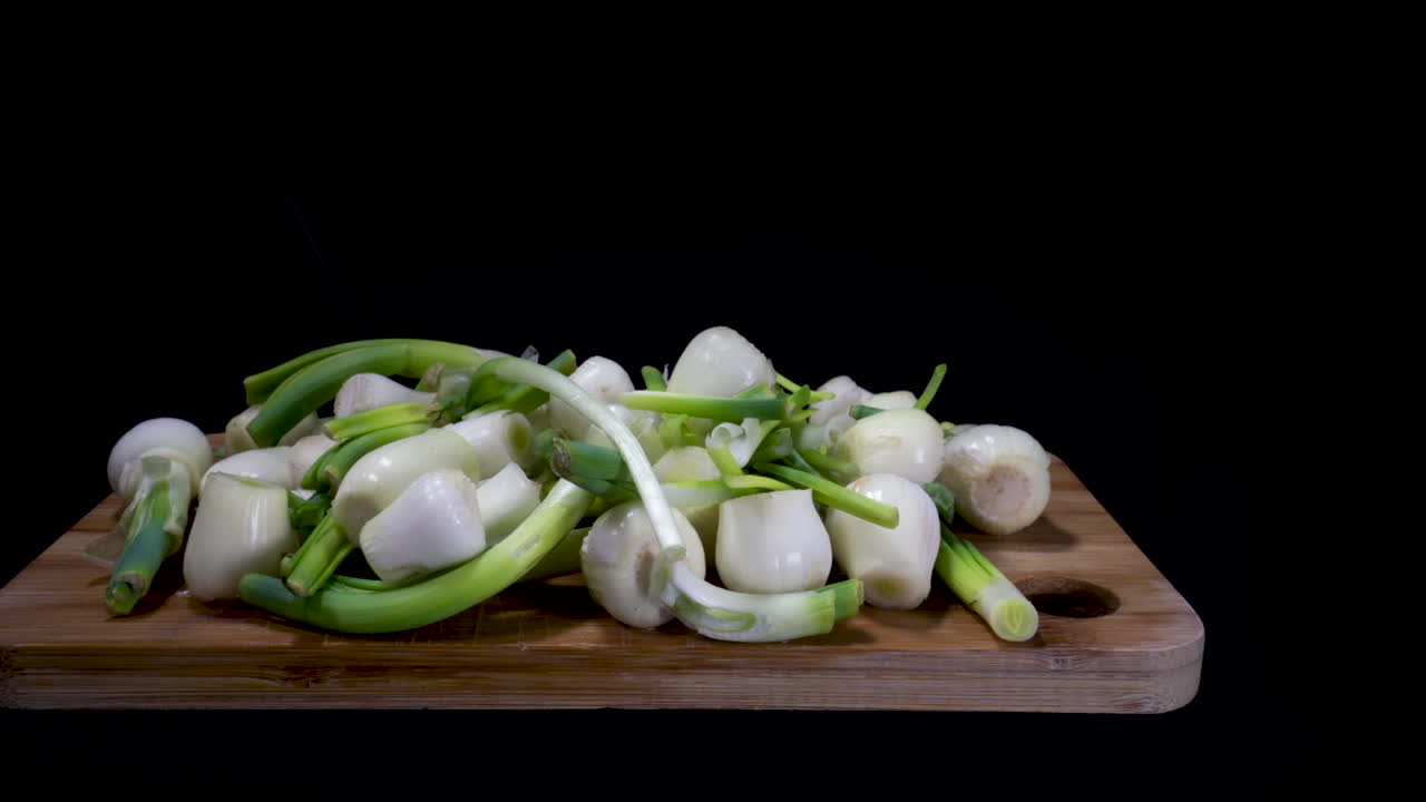 Fresh Peeled White Onions Over The Wooden Cutting Board Isolated In Black Background. - panning shot left to right