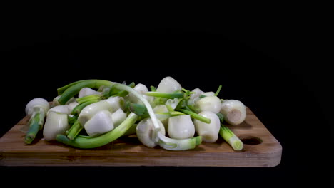 fresh peeled white onions over the wooden cutting board isolated in black background. - panning shot left to right