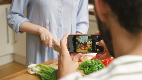 a man recording a video of his girlfriend cooking