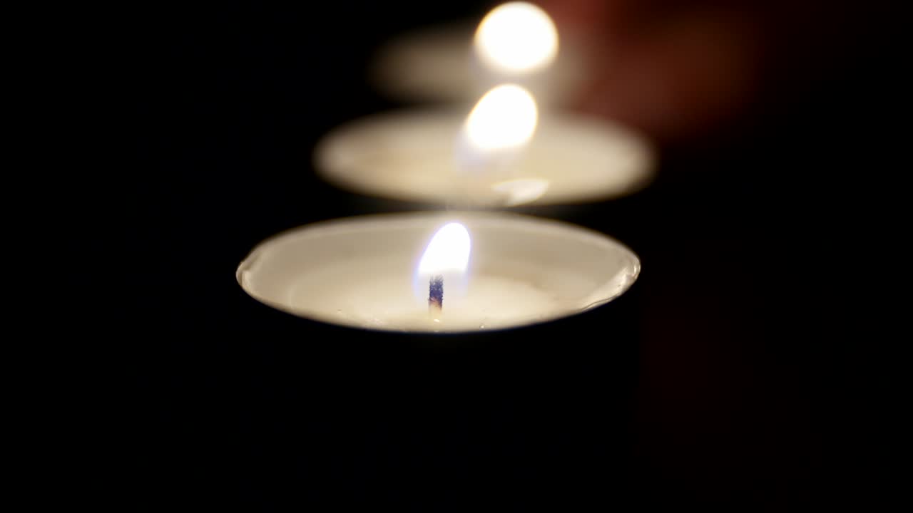 Lume di candela. Piccole candele allineate si accendono una ad una.