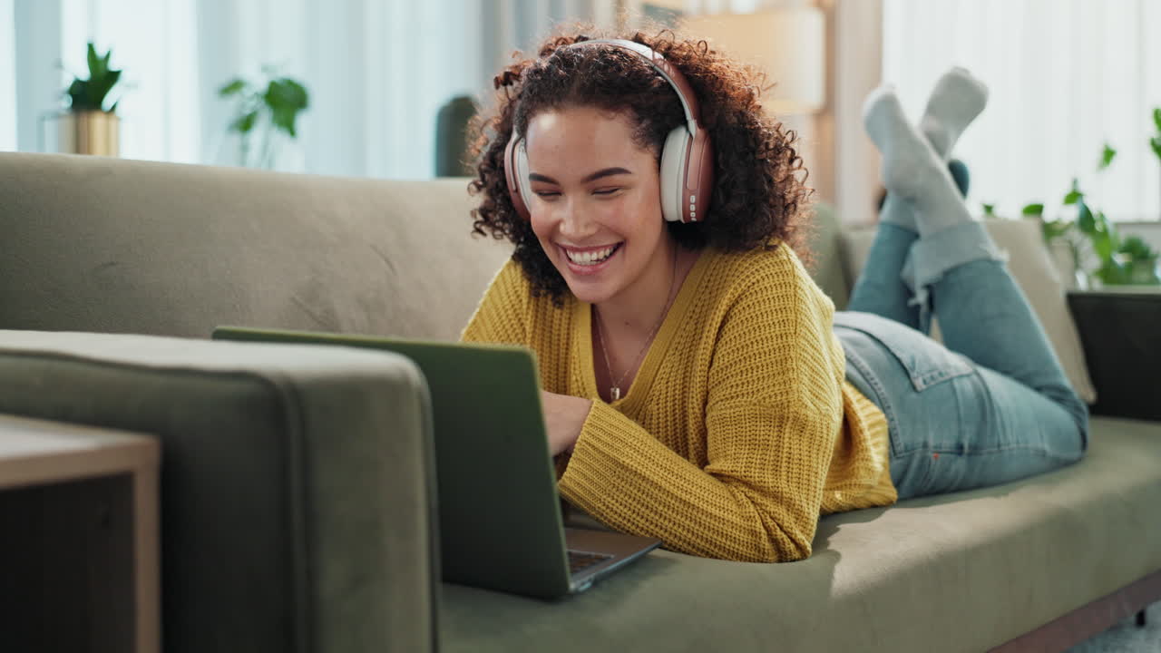 Woman relaxing on couch with laptop and headphones