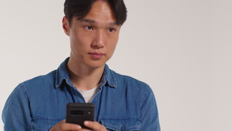 man with mobile phone in front of white studio background posing for photo booth style portraits 2