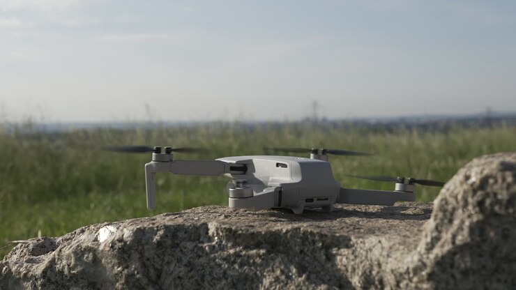 Primo piano di un drone quadricottero che decolla da una roccia in un campo di campagna in una giornata di sole.