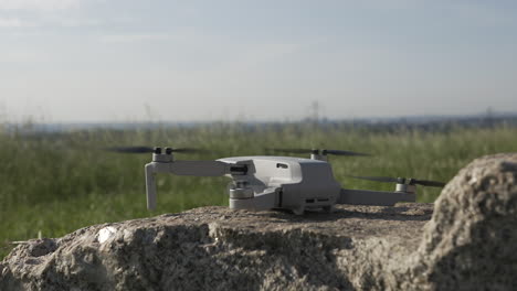 drone quadcopter taking off from rock in countryside field on sunny day close up