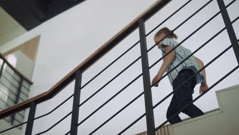 niño activo bajando las escaleras al pasillo. niño preadolescente saltando después de las lecciones.