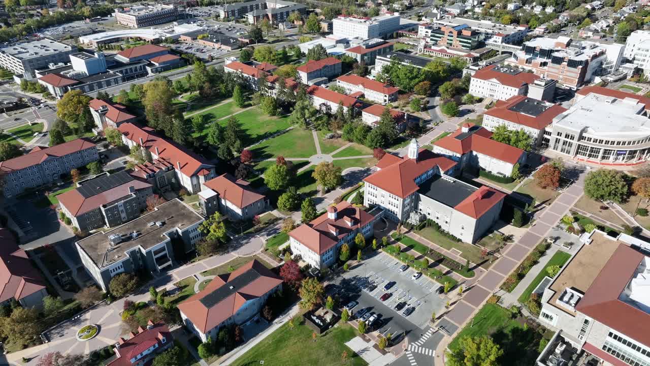 James Madison University with green inner yard in city of Harrisonburg, Virginia. Aerial tilt up wide shot. Sunny day in american town. White facade of buildings and orange tile roof. Rising shot
