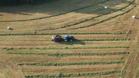 the tractor moving slowly, harvesting grass and packaging it into neat white plastic rolls