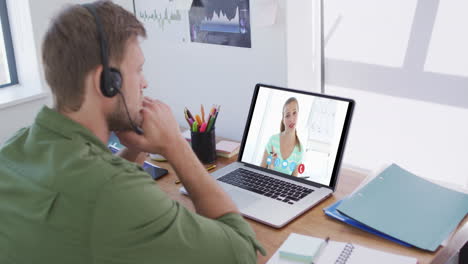hombre caucásico usando computadora portátil y auriculares de teléfono en videollamada con una colega