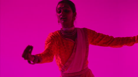 Waist-Up-Studio-Shot-Of-Female-Kathak-Dancer-Performing-Dance-Wearing-Traditional-Indian-Dress-Against-Purple-Background-2