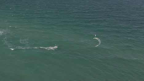 aerial: kite surfer steers kite to take him into deeper water in miami