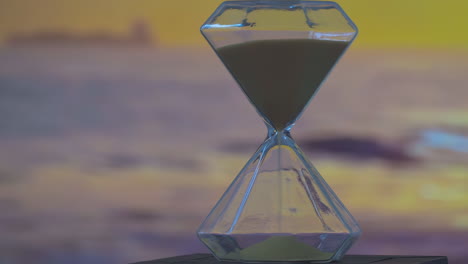 Close-of-hourglass-with-sand-running-through-it,-measuring-the-passage-of-time-as-gravity-pulls-the-granules-from-one-chamber-to-another