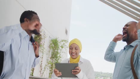 happy diverse business people celebrating and using tablet at office, slow motion