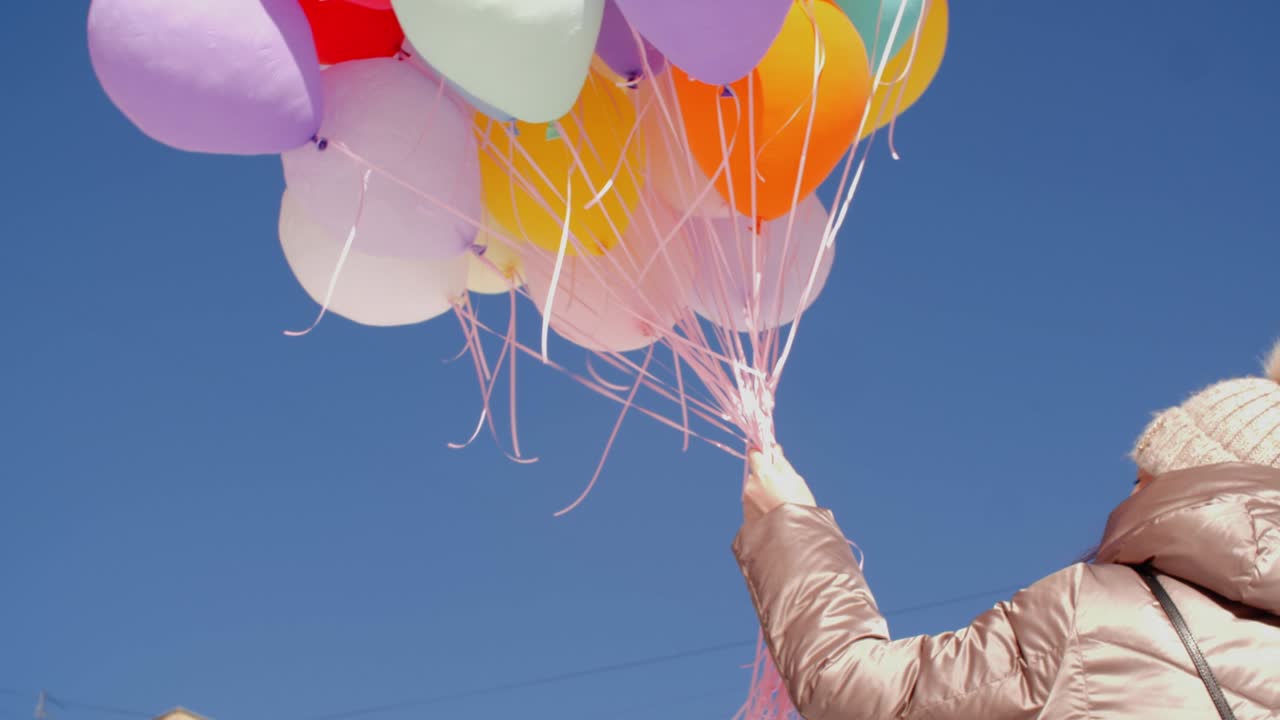 vista de ángulo bajo de la mujer sosteniendo un montón de globos