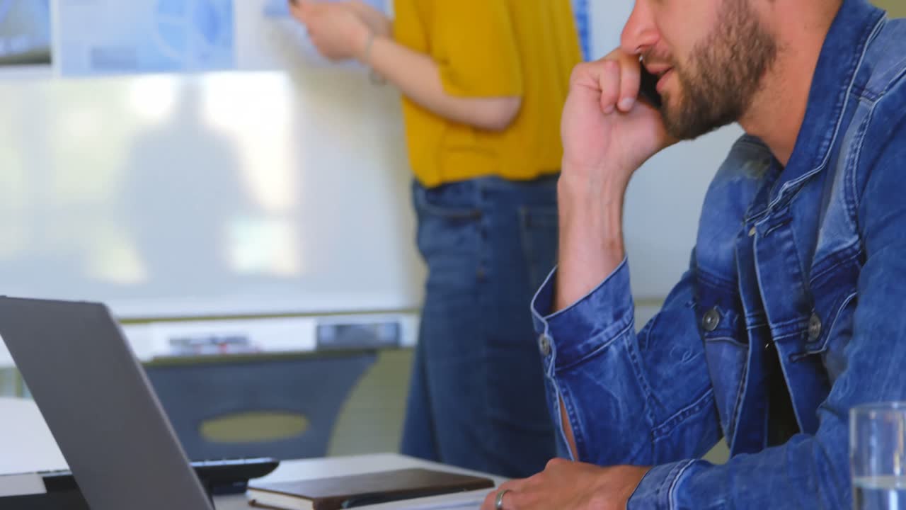 vista lateral de un joven hombre de negocios caucásico hablando por teléfono móvil en una oficina moderna 4k