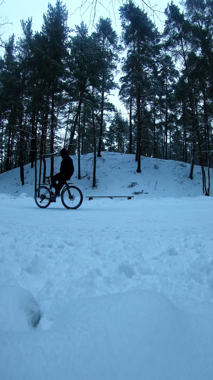 Static winter Riga shot of cyclist riding backwards symbolizing human resilience