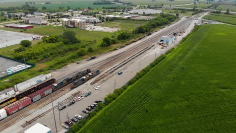 4K-Seitenansicht-Eines-Langsam-Anfahrenden-Zuges,-Der-Einen-Bahnhof-Neben-Einer-Kleinen-Stadt-Verlässt