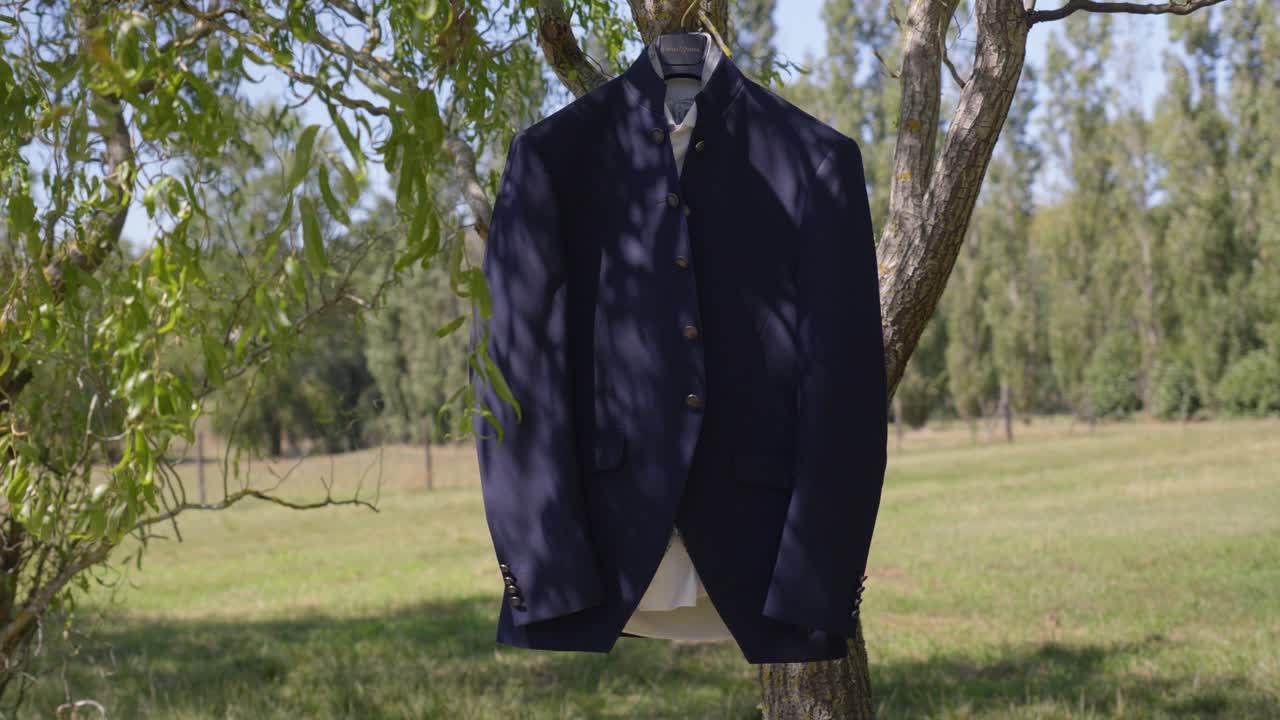 Elegant blue wedding suit hanging on a tree inside the park.