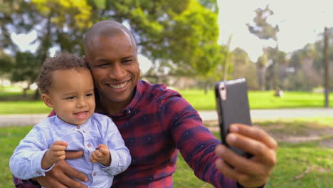 Vater-Sitzt-Auf-Den-Hüften,-Hält-Seinen-Sohn-Auf-Knien-Und-Macht-Ein-Selfie