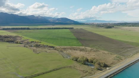 aerial view of flat plateau of green agricultural fields at the base of the southern alps in rural mackenzie district, south island of new zealand aotearoa