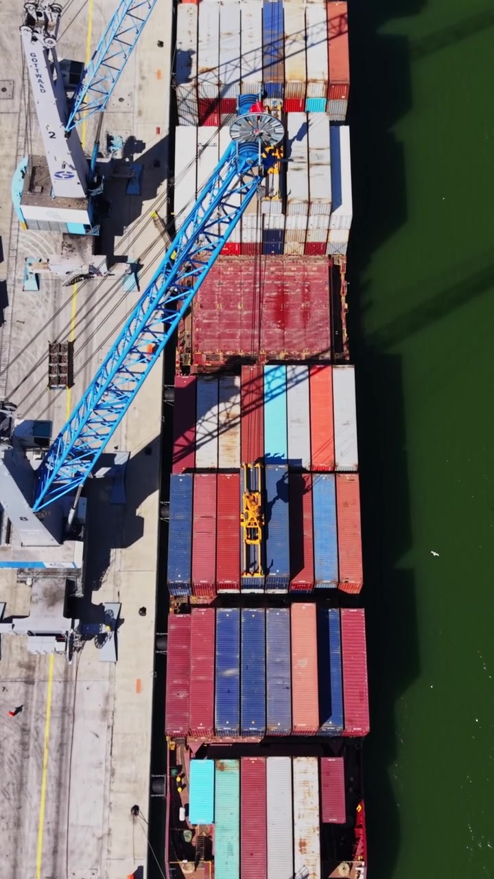 Cargo ship loads containers at port during sunny day