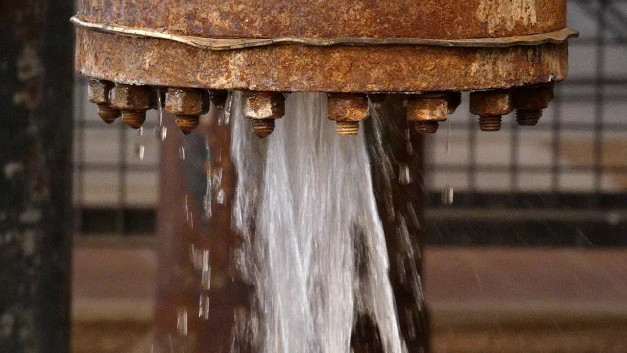 Water gushing out of old rusty pipe leaking or bad maintenance slow motion