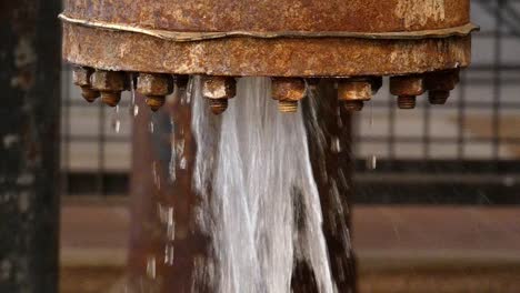 agua brotando de la vieja tubería oxidada con fugas o mal mantenimiento a cámara lenta