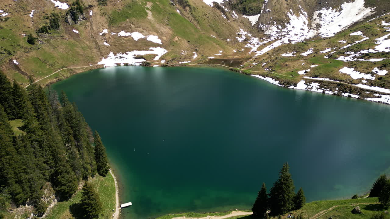 Crane up drone shot of Lake Lioson during the day with snow in Ormont-Dessous, near Les Mosses, in the canton of Vaud, Switzerland