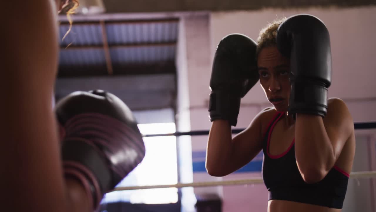 Duas mulheres mestiças treinando no ringue de boxe
