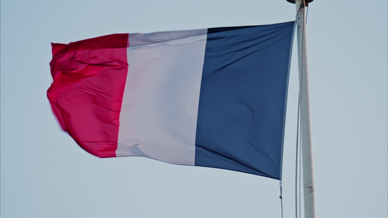 Primer plano de la bandera francesa ondeando con el cielo azul de fondo