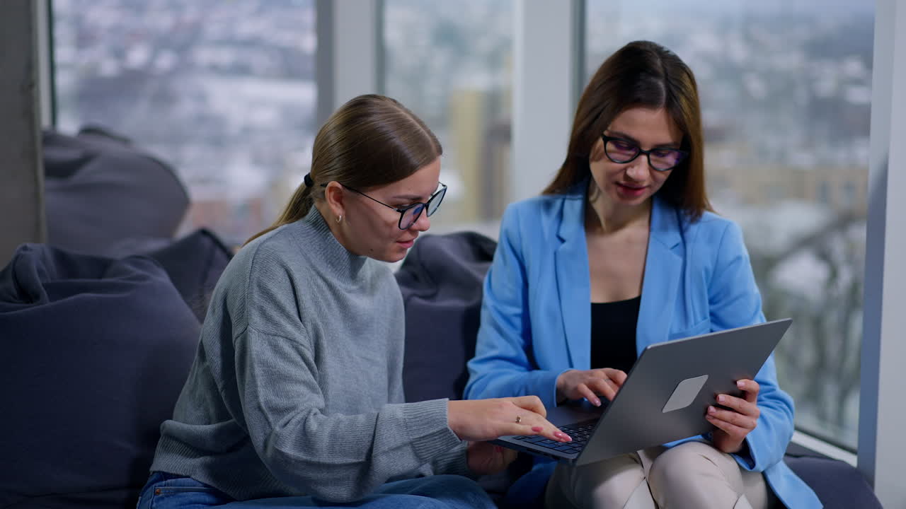 Two Women Collaborating on a Laptop in a Modern Office