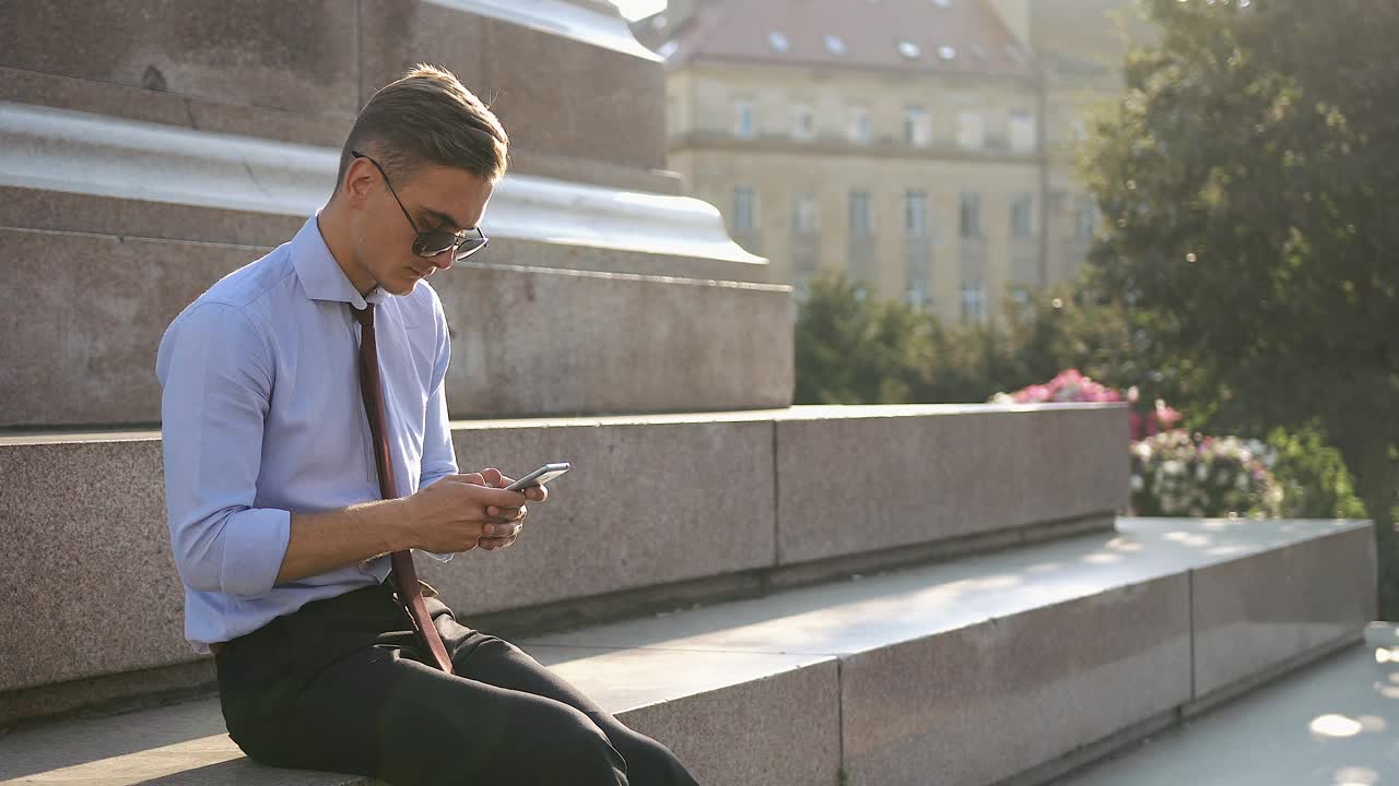 Businessman texting on stairs in the city