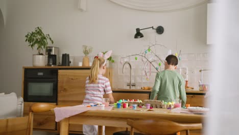 children painting easter eggs in kitchen