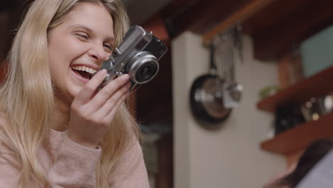 happy young couple taking photos together using camera having fun at home on sofa playfully enjoying romantic relationship photographing each other making faces