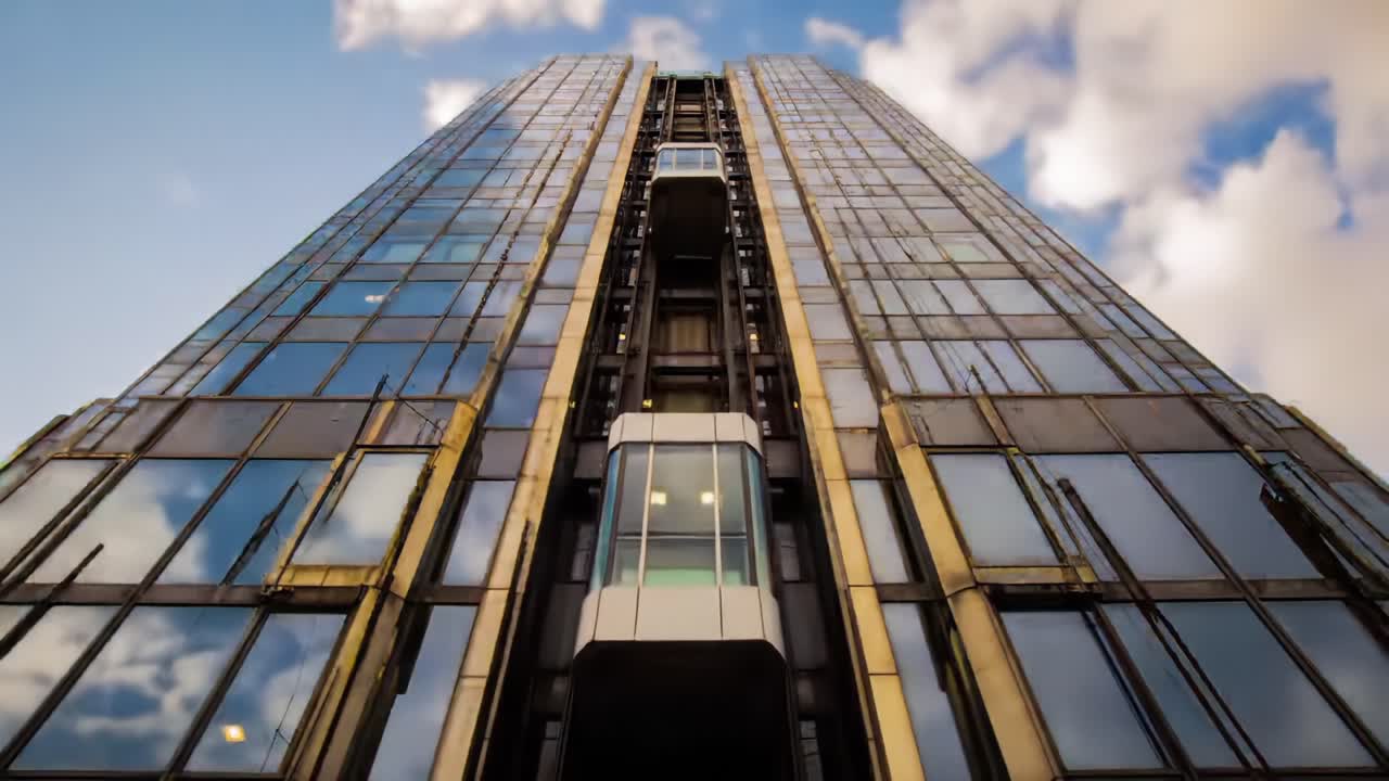 A Stunning View of a Modern Skyscraper with an Impressive Glass Facade and Captivating Elevator System Against a Dramatic Sky Background